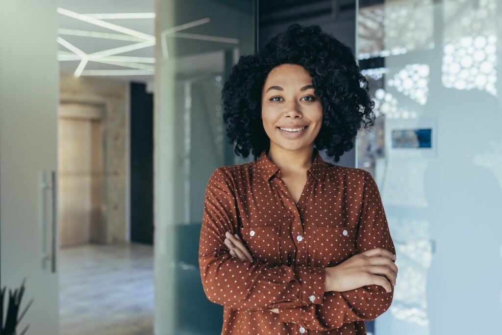 Portrait of happy and successful business woman, boss in shirt smiling and looking at camera inside